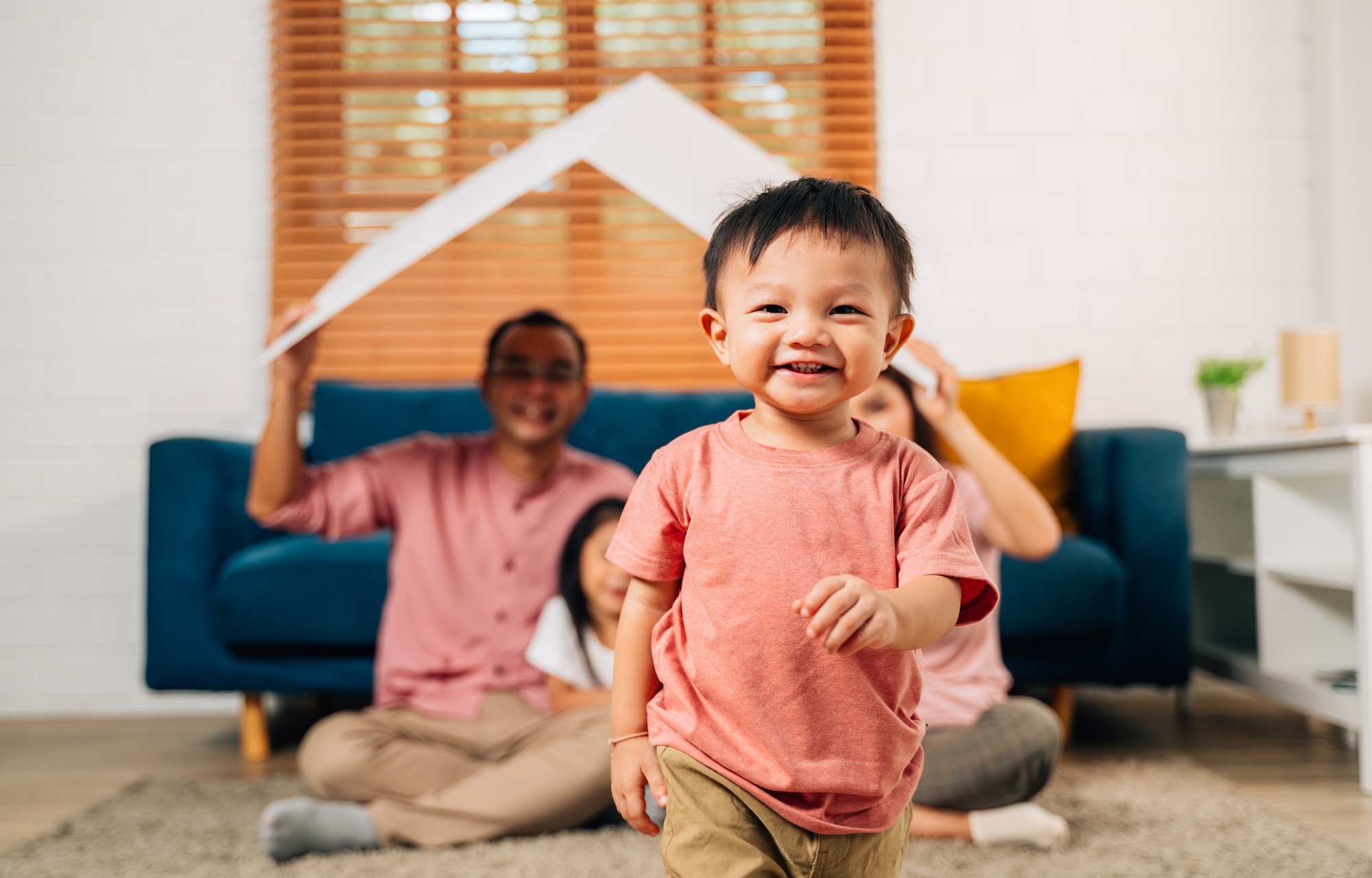 Happy family holding symbolic cardboard roof of life insurance